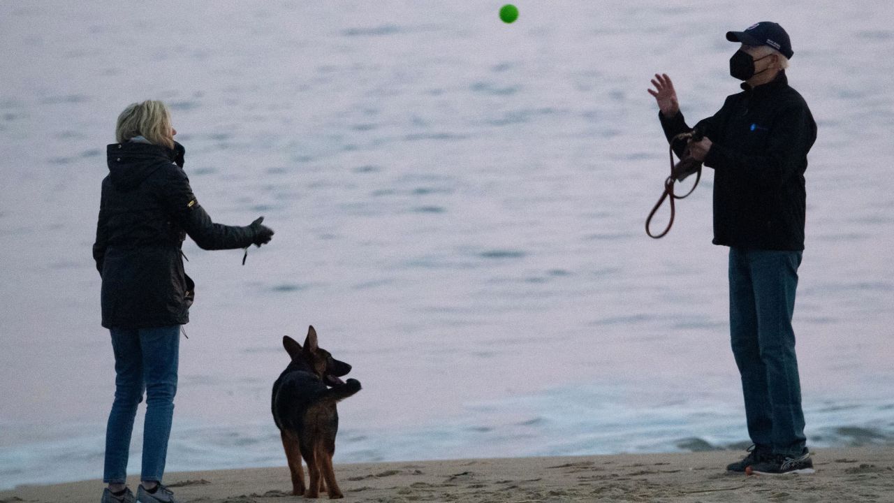 US President Joe Biden and US First Lady Jill Biden, play with their dog Commander at Rehoboth Beach, Delaware, on December 28, 2021.
